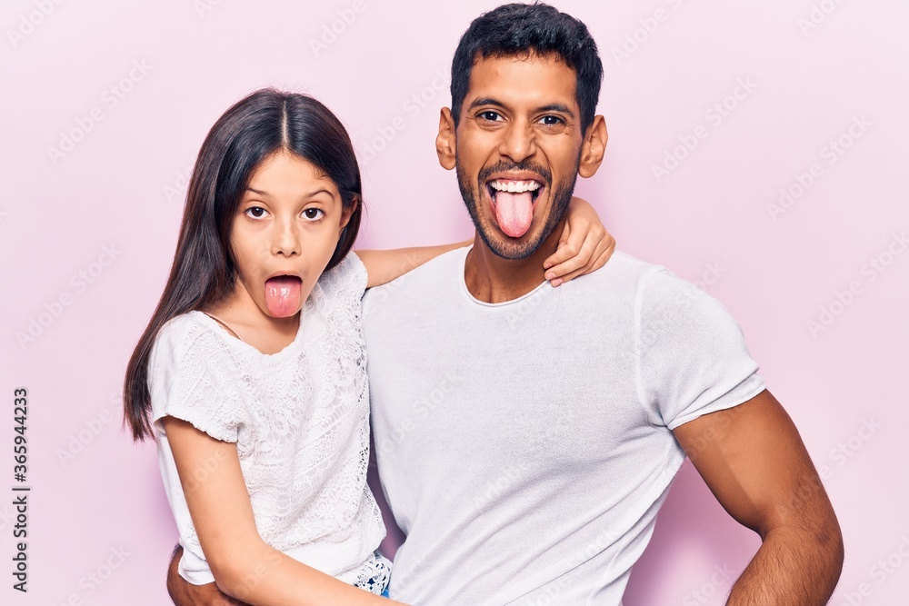 Young father and daughter wearing casual clothes sticking tongue out happy with funny expression. emotion concept. Young father and daughter wearing casual clothes sticking tongue out happy with funny expression. emotion concept.