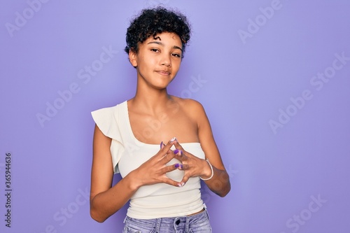 Young beautiful african american afro woman wearing casual t-shirt over purple background Hands together and fingers crossed smiling relaxed and cheerful. Success and optimistic