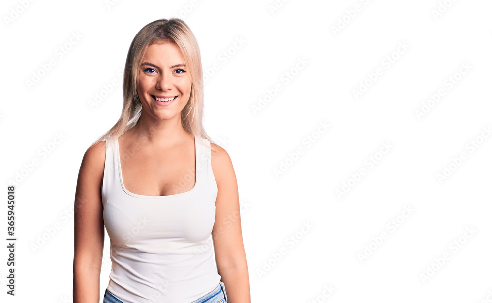 Young beautiful blonde woman wearing casual sleeveless t-shirt with a happy and cool smile on face. lucky person. Young beautiful blonde woman wearing casual sleeveless t-shirt with a happy and cool smile on face. lucky person.