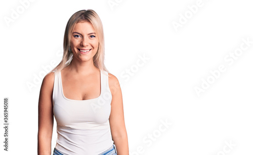 Young beautiful blonde woman wearing casual sleeveless t-shirt with a happy and cool smile on face. lucky person.