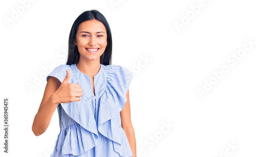 Young beautiful latin girl wearing casual clothes doing happy thumbs up gesture with hand. approving expression looking at the camera showing success. © Krakenimages.com