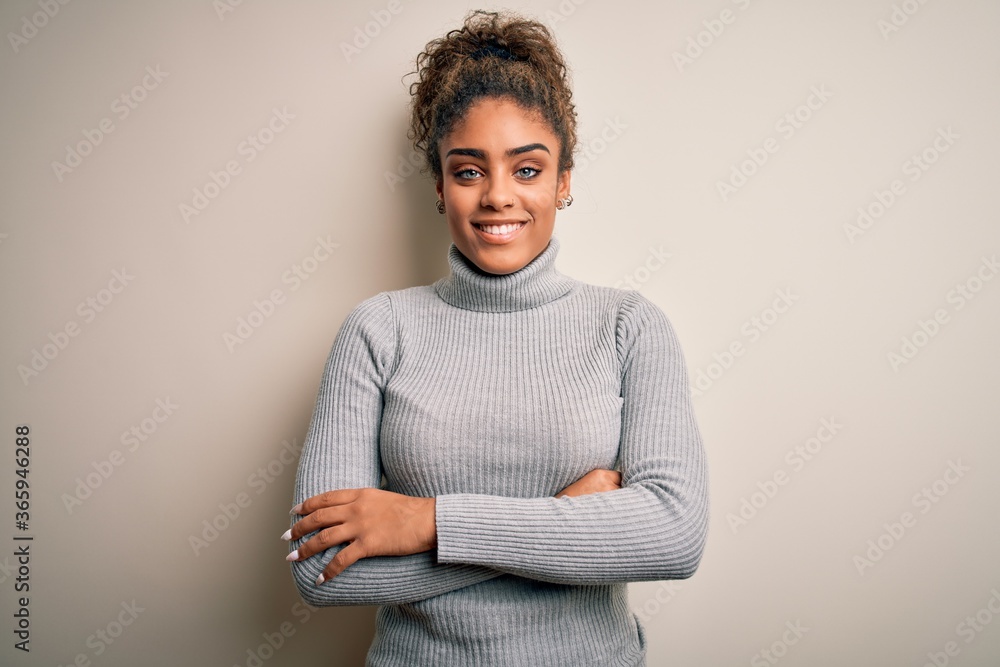 Beautiful african american girl wearing turtleneck sweater standing over  white background happy face smiling with crossed arms looking at the  camera. Positive person. Stock Photo