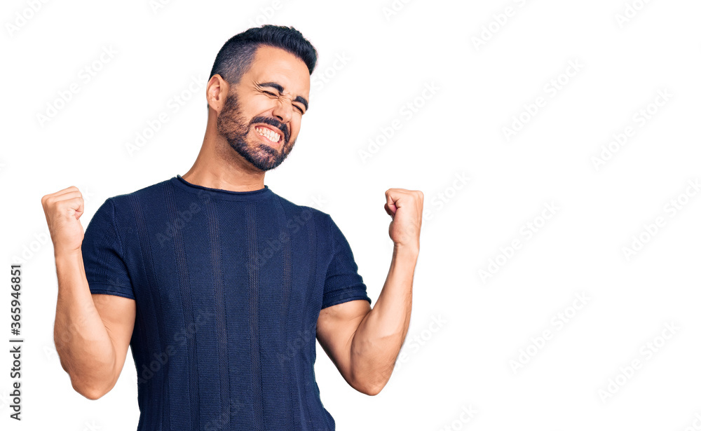 Young hispanic man wearing casual clothes very happy and excited doing winner gesture with arms raised, smiling and screaming for success. celebration concept. Young hispanic man wearing casual clothes very happy and excited doing winner gesture with arms raised, smiling and screaming for success. celebration concept.