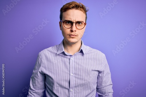 Young handsome redhead man wearing casual shirt and glasses over purple background skeptic and nervous, frowning upset because of problem. Negative person. © Krakenimages.com
