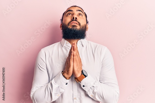 Young arab man wearing casual clothes begging and praying with hands together with hope expression on face very emotional and worried. begging.