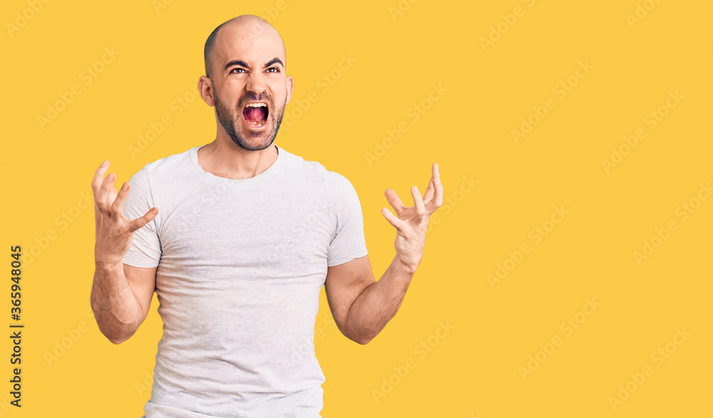 Young handsome man wearing casual t shirt crazy and mad shouting and yelling with aggressive expression and arms raised. frustration concept. Young handsome man wearing casual t shirt crazy and mad shouting and yelling with aggressive expression and arms raised. frustration concept.
