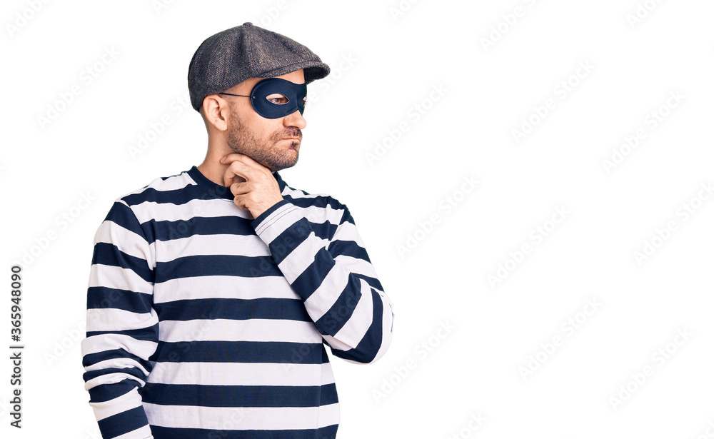 Young handsome man wearing burglar mask touching painful neck, sore throat for flu, clod and infection Young handsome man wearing burglar mask touching painful neck, sore throat for flu, clod and infection