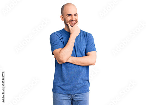 Young handsome man wearing casual t shirt looking confident at the camera smiling with crossed arms and hand raised on chin. thinking positive.