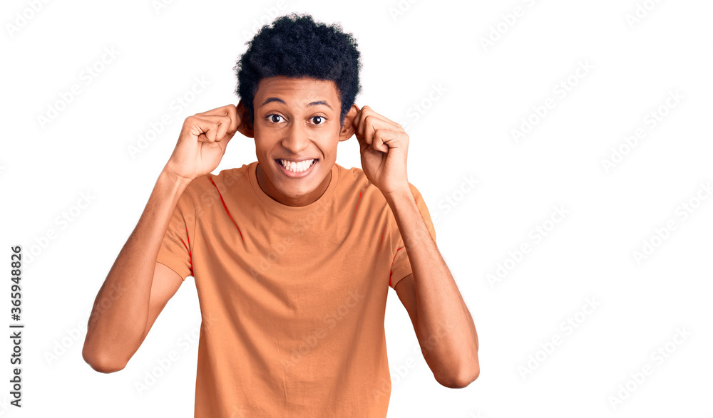Young african american man wearing casual clothes smiling pulling ears with fingers, funny gesture. audition problem Young african american man wearing casual clothes smiling pulling ears with fingers, funny gesture. audition problem