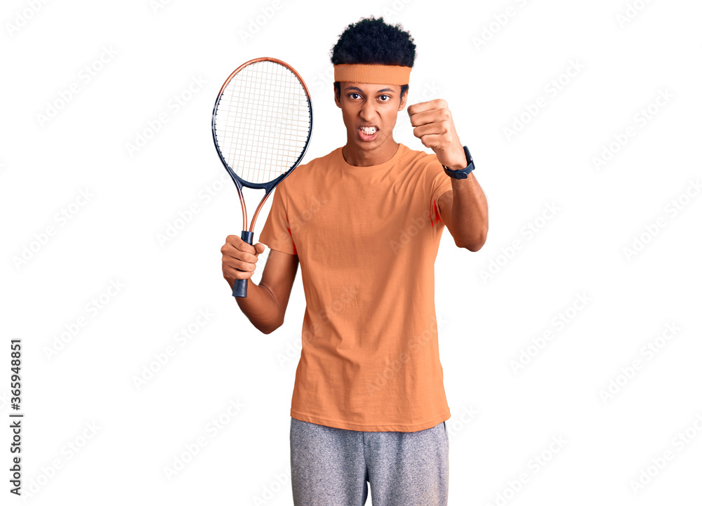Young african american man playing tennis holding racket annoyed and frustrated shouting with anger, yelling crazy with anger and hand raised Young african american man playing tennis holding racket annoyed and frustrated shouting with anger, yelling crazy with anger and hand raised