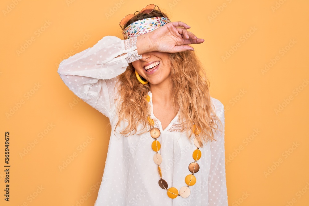 Young beautiful blonde hippie woman with blue eyes wearing sunglasses and accessories covering eyes arm and funny. Blind concept. Stock Photo | Adobe Stock