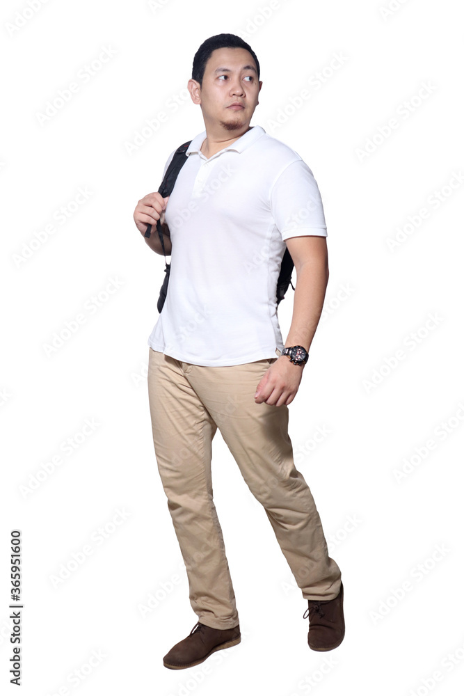 Full length portrait of Asian man wearing white shirt, khaki jeans and backpack standing walking, side view Full length portrait of Asian man wearing white shirt, khaki jeans and backpack standing walking, side view