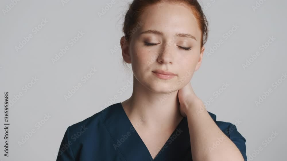 Young beautiful tired female doctor feeling pain in neck over white background Young beautiful tired female doctor feeling pain in neck over white background