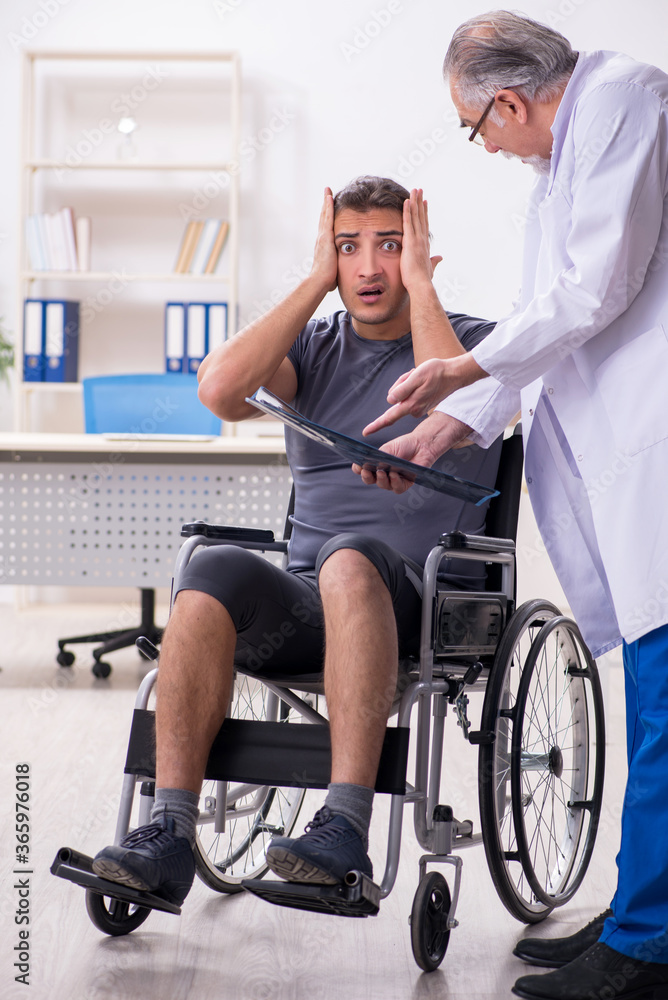 Young male patient in wheel-chair visiting old doctor radiologis Young male patient in wheel-chair visiting old doctor radiologis