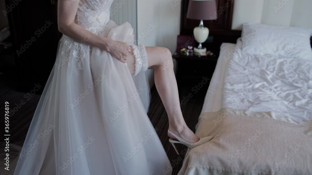 bride puts a garter on her leg bride puts a garter on her leg