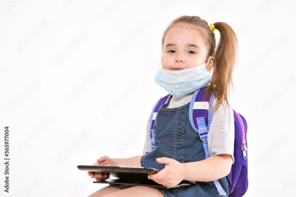 1 September. a first-grader in medical school is going to school. a little girl on home distance learning. A child with a backpack is working on a laptop. the student is doing homework. isolated on a 1 September. a first-grader in medical school is going to school. a little girl on home distance learning. A child with a backpack is working on a laptop. the student is doing homework. isolated on a