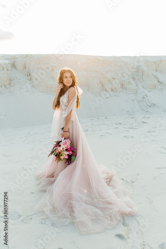 Love Story of a beautiful couple in a pink wedding luxury dress with a bouquet in the Sahara desert, sand, dunes