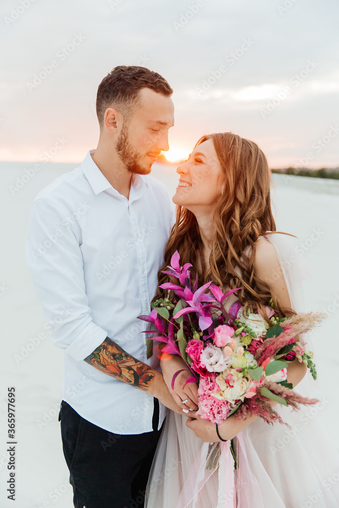 Love Story of a beautiful couple in a pink wedding luxury dress with a bouquet in the Sahara desert, sand, dunes Love Story of a beautiful couple in a pink wedding luxury dress with a bouquet in the Sahara desert, sand, dunes
