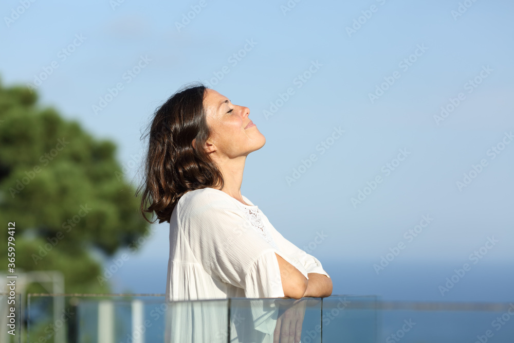 Adult woman breathing fresh air in a balcony on the beach