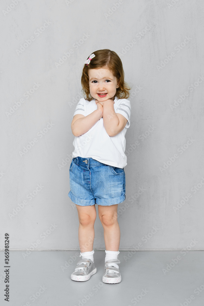 Two years old girl in t-short and jeans shorts posing in studio Two years old girl in t-short and jeans shorts posing in studio