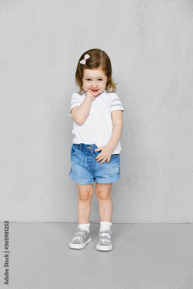 Two years old girl in t-short and jeans shorts posing in studio Two years old girl in t-short and jeans shorts posing in studio