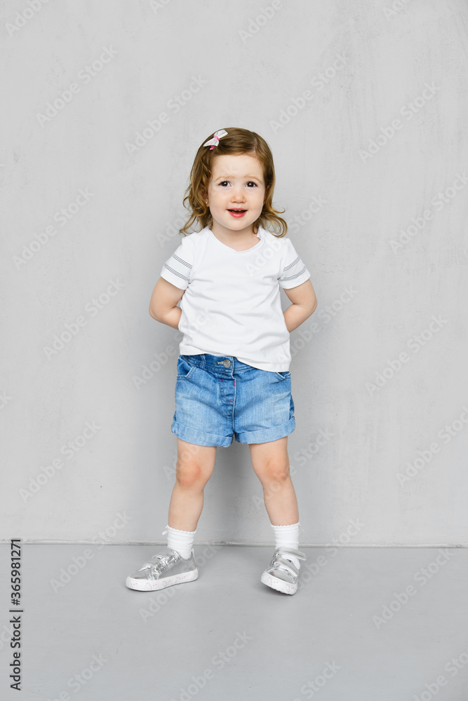 Two years old girl in t-short and jeans shorts posing in studio Two years old girl in t-short and jeans shorts posing in studio
