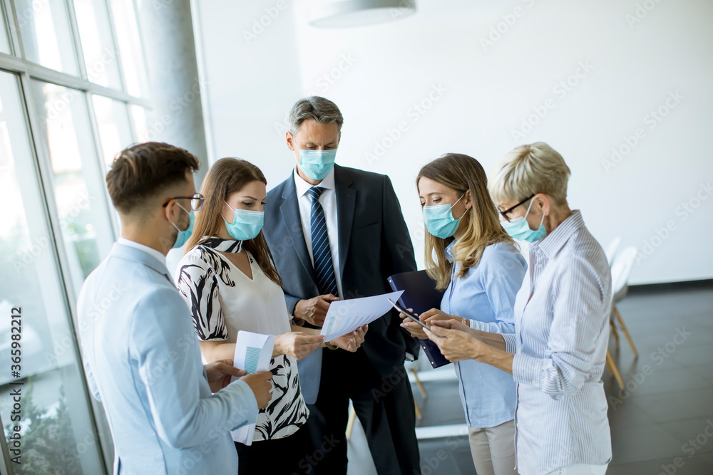 Business partners standing and looking at business results in office while wearing face masks sa an virus protection Business partners standing and looking at business results in office while wearing face masks sa an virus protection