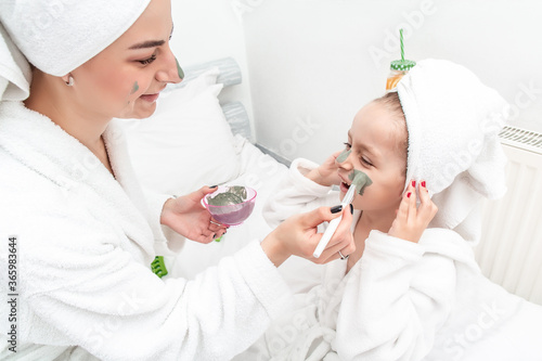 Mother with child doing beauty treatment together. Happy family mother and child daughter make face skin mask. beauty salon concept, wellness spa