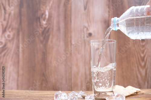 Pouring drinking water in glasses on wood table background and space for text