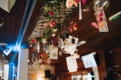 Garlands of retro lamps on the bar. Decorated with flowers and postcards.