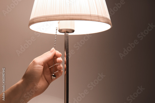 Fotografie Woman turning on glowing lamp, closeup