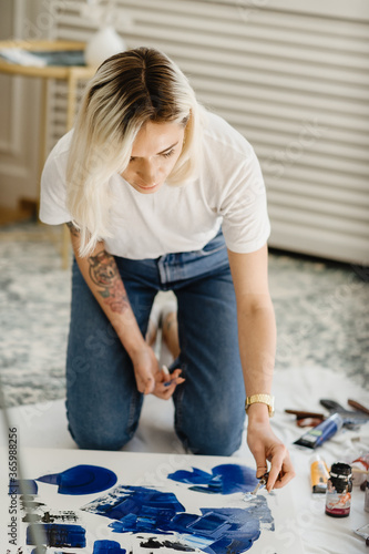 Beautiful young woman artist drawing in a comfy home interior