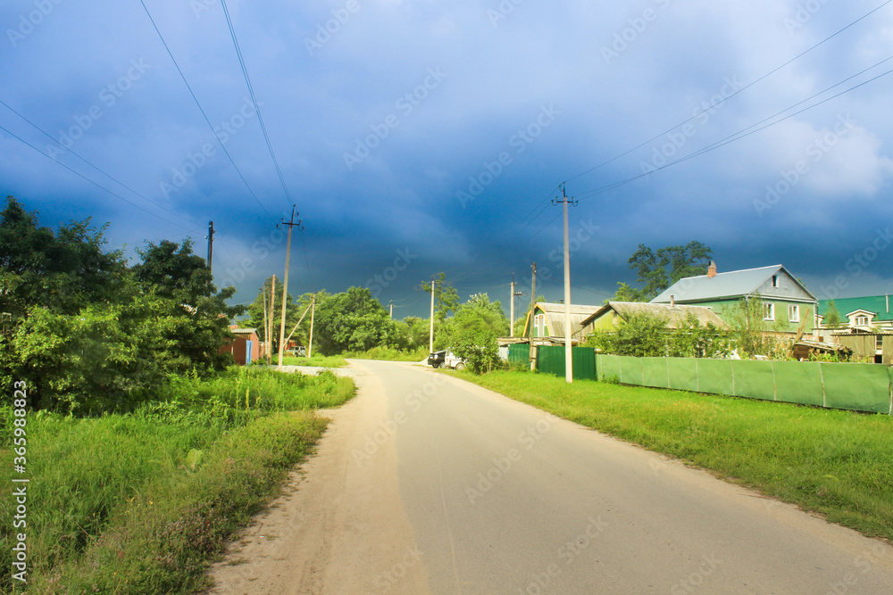 village road, forest and sky in clouds