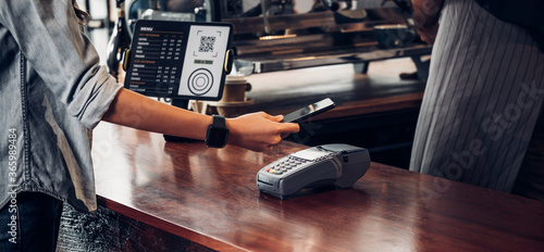 customer contactless payment for drink with mobile phon at cafe counter bar,seller coffee shop accept payment by mobile.new normal lifestyle concept photo