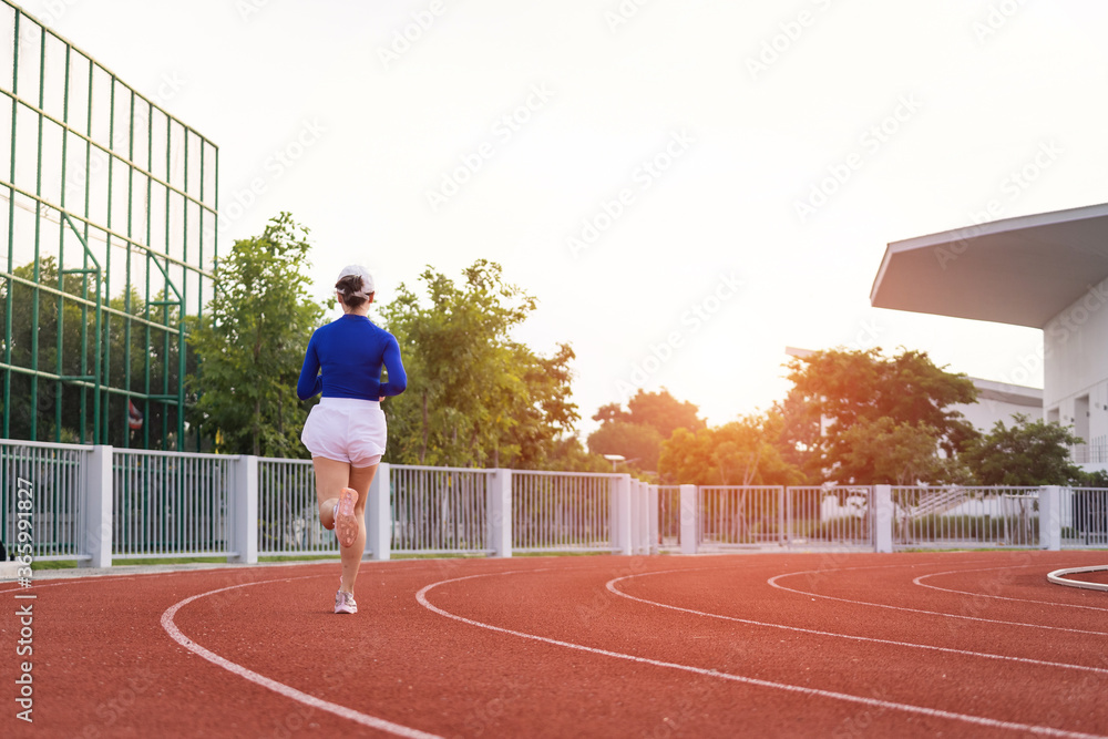 Obraz premium Young fitness woman runner jogging excercise in the morning on city stadium track in the city. Female athlete excercise in the city stadium to keep body fitness. Health and recreation stock photo.