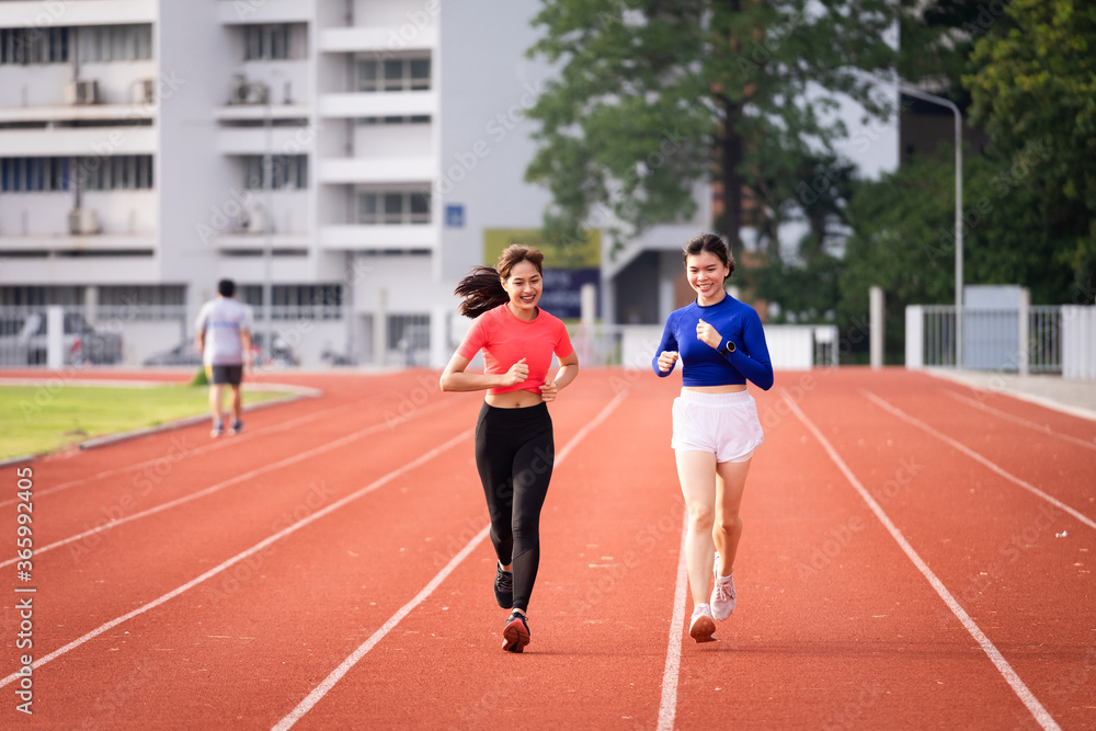 Young fitness woman runner jogging excercise in the morning on city stadium track in the city. Female athlete excercise in the city stadium to keep body fitness.  Stock photo.