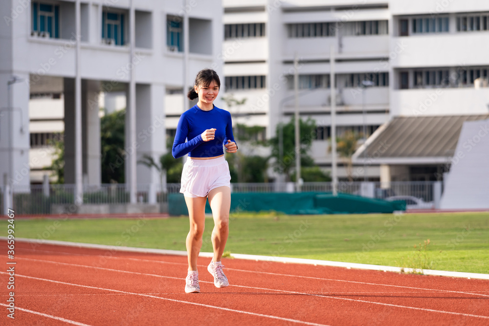 Young fitness woman runner jogging excercise in the morning on stadium track in the city. Female athlete excercise in the city stadium to keep body fitness during COVID-19 pandemic. Stock photo.