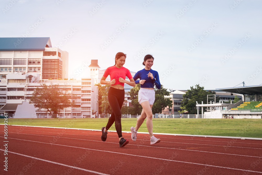 Young fitness woman runner jogging excercise in the morning on city stadium track in the city. Female athlete excercise in the city stadium to keep body fitness.  Stock photo.