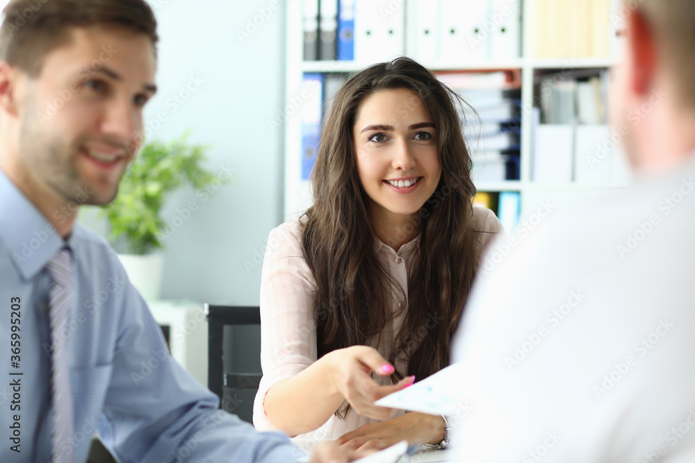 Cheerful two men and woman team workers are discussing company projects in comfortable room at table Cheerful two men and woman team workers are discussing company projects in comfortable room at table