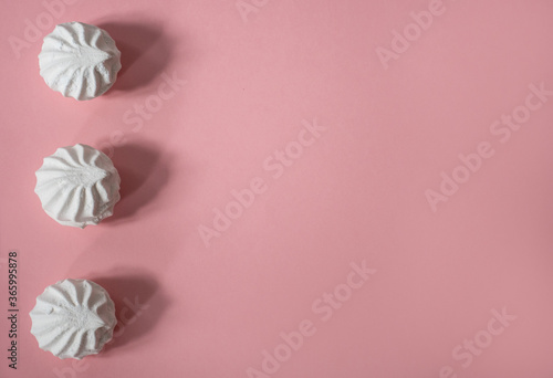 Three white large and delicious hand-made marshmallows lie vertically above each other on a pink background: sweet background, seamless pattern, space for text