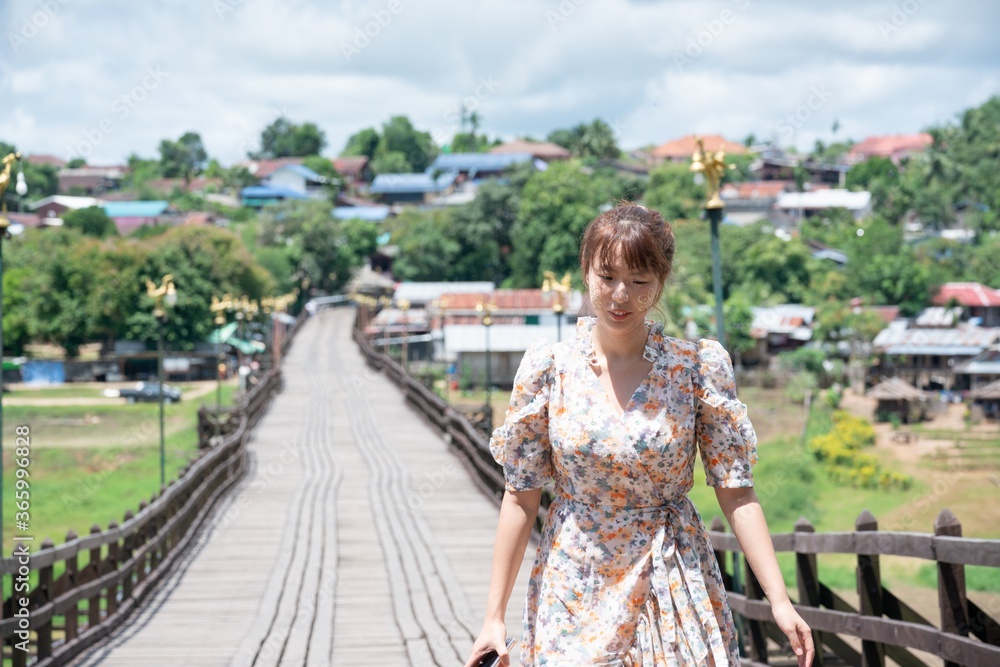 Cute asian woman wear casual posting alone on wooden bridge at Sangkhaburi, Kanchanaburi, Thailand.
