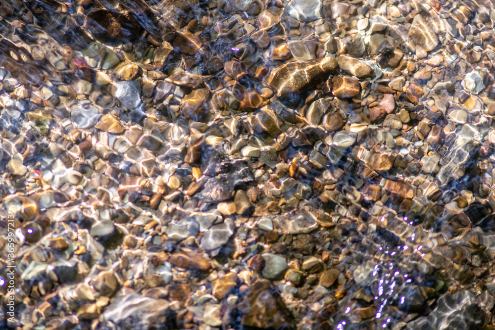Silky ripples in water of a crystal clear water creek as idyllic natural background with high angle view shows zen meditation and little waves in a healthy mountain spring with a clear floating stream Silky ripples in water of a crystal clear water creek as idyllic natural background with high angle view shows zen meditation and little waves in a healthy mountain spring with a clear floating stream