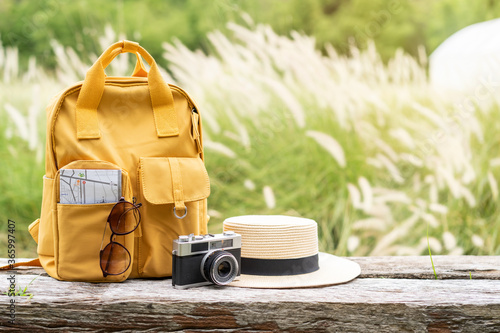 Travel backpack with traveler items on wooden bench with nature background and copy space photo