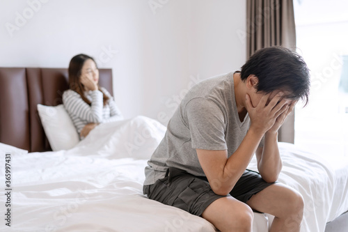 Husband feels stressed and pressured from the problem of erectile dysfunction while the disgruntled wife lay in bed after having sex