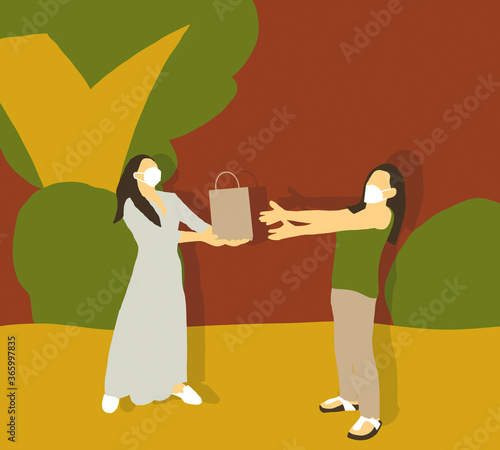 Two woman wearing protective face mask passing brown paper bag at park in autumn during quarantine to avoid physical contact.Coronavirus COVID-19 disease protection.Social distancing practice.