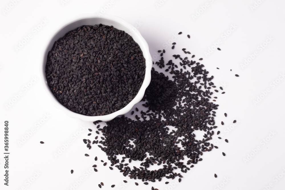Black sesame seeds in a white ceramic cup on a white background Black sesame seeds in a white ceramic cup on a white background