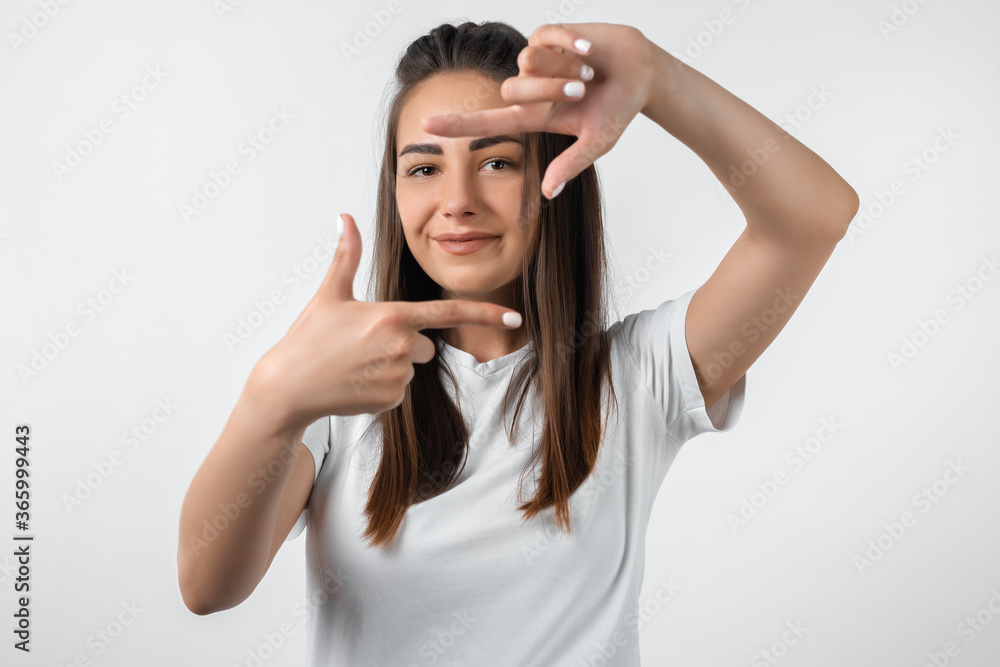 Portrait positive of young woman with long chestnut hair with cheerful expression. Gesturing finger frame. Beautiful young woman looking at camera and gesturing finger frame Portrait positive of young woman with long chestnut hair with cheerful expression. Gesturing finger frame. Beautiful young woman looking at camera and gesturing finger frame