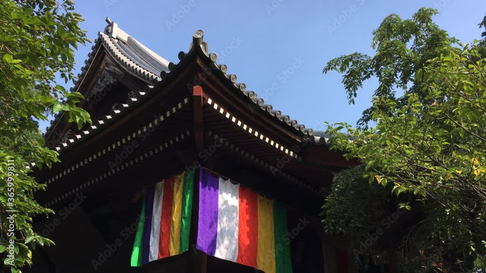 Kobuchi Kannon Temple's roofs and colorful curtains with blue sky and green trees. Kasukabe, Saitama, Japan, July 20, 2020 Kobuchi Kannon Temple's roofs and colorful curtains with blue sky and green trees. Kasukabe, Saitama, Japan, July 20, 2020