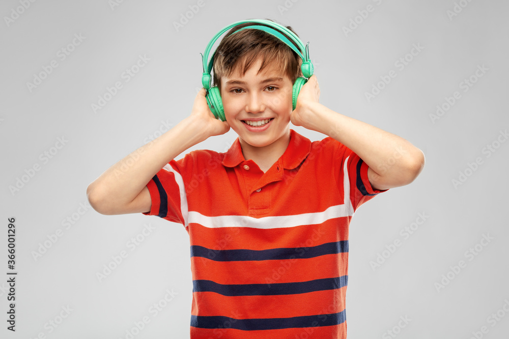 audio equipment and technology people concept - happy smiling boy in headphones listening to music over grey background audio equipment and technology people concept - happy smiling boy in headphones listening to music over grey background