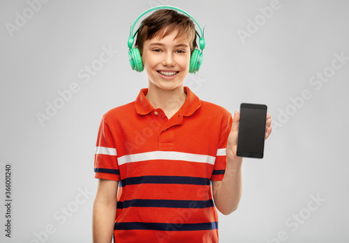 audio equipment and technology people concept - happy smiling boy in headphones listening to music on smartphone over grey background